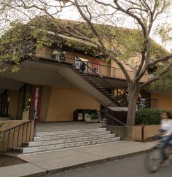 Someone bikes past Tresidder Union, a central space on campus that has dining options and ATMs.