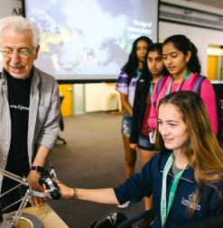 A participant handles a robotic remote while a researcher and other participants look on.